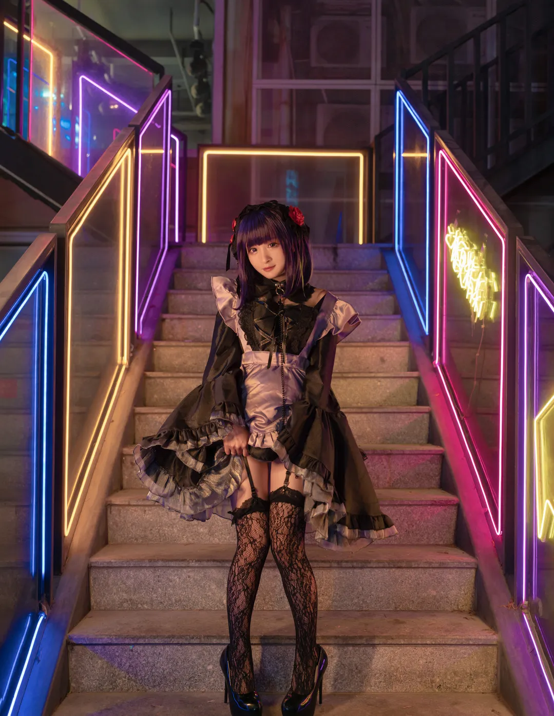 九九八XY海外Coser 九九八XY暗色角色造型照片,黑色裙装搭配深色发型,位于霓虹灯楼梯空间
